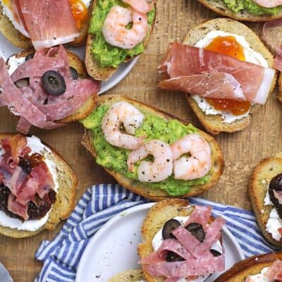 A board of four different kinds of crostini appetizers.