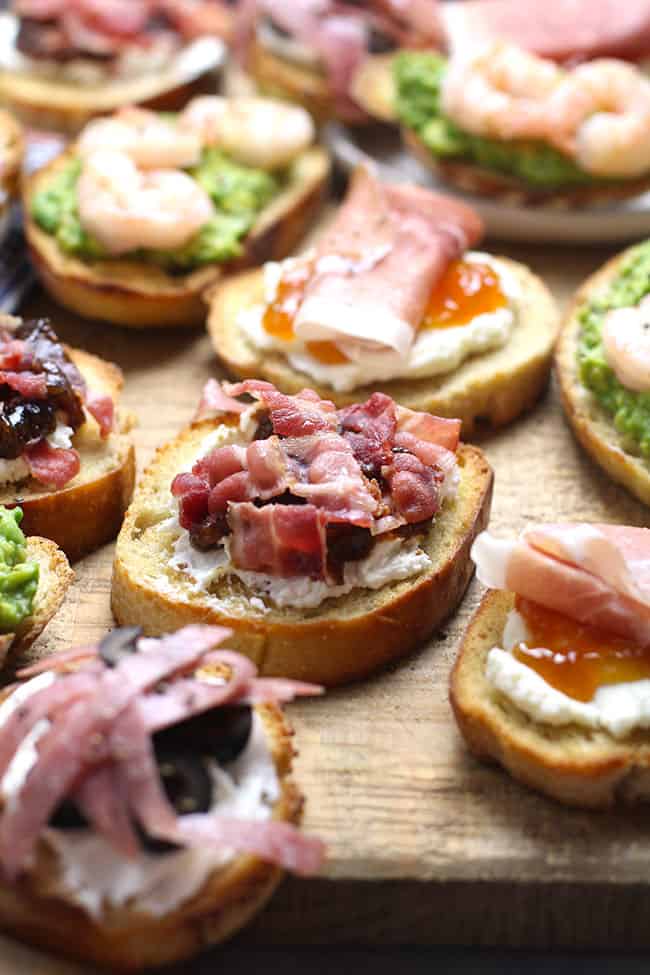 Side shot of a board of crostini, four ways.