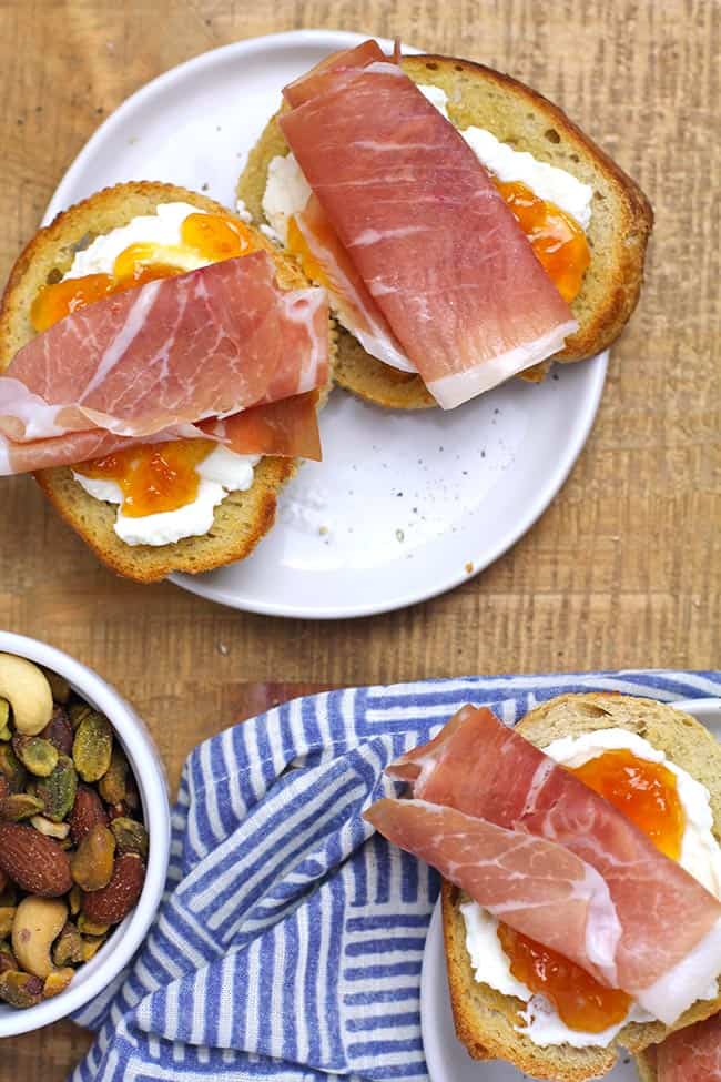 Two plates of prosciutto goat cheese crostini with apricot preserves.
