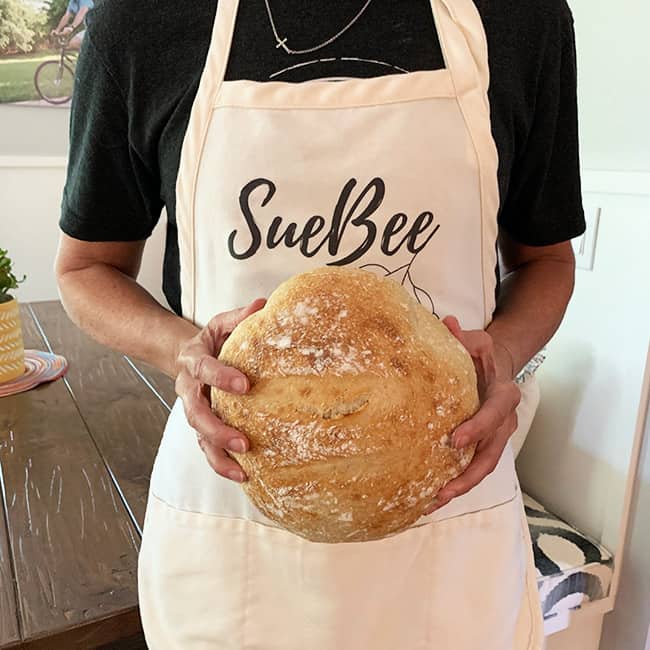 Me with my SueBee apron on holding a loaf of sourdough.