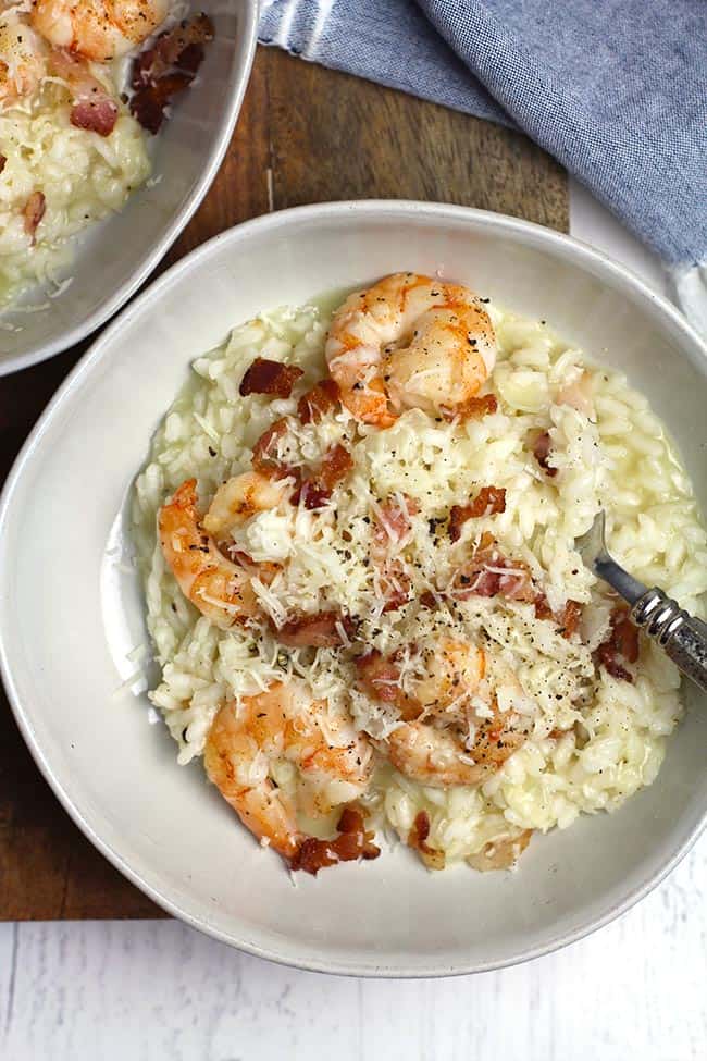 Overhead shot of two bowls of creamy shrimp risotto with bacon.