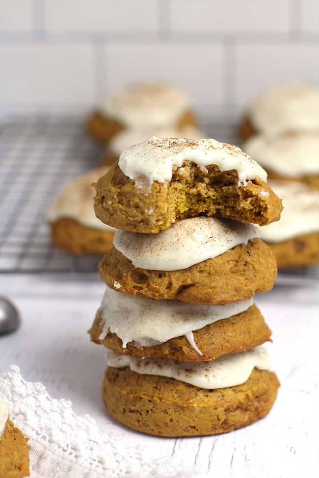 A stack of four pumpkin cookies with icing.