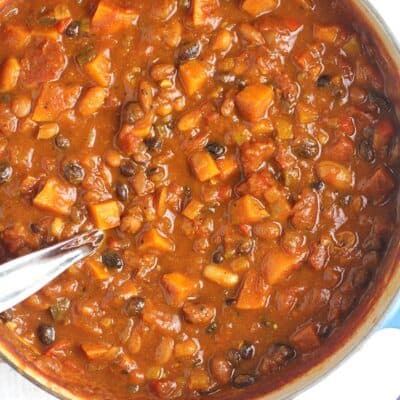 A big stock pot of 3-Bean Pumpkin Chili, with a soup ladle inside.