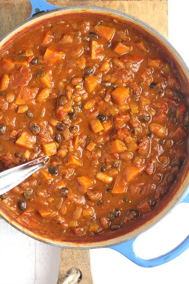 A big stock pot of 3-Bean Pumpkin Chili, with a soup ladle inside.