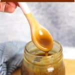 A spoon of drizzling caramel sauce in a jar.