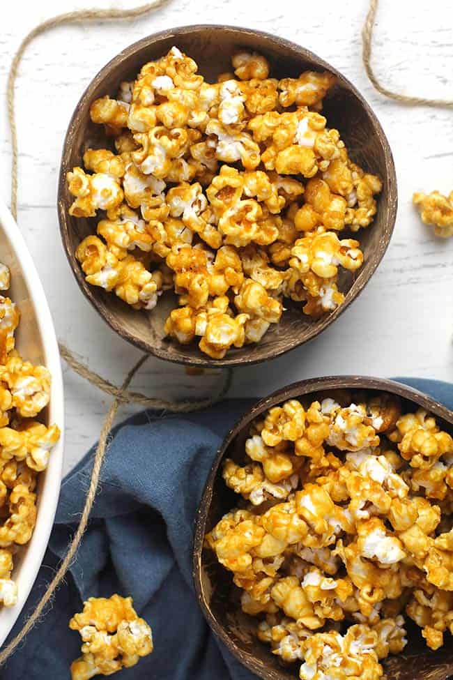 Two bowls of homemade caramel popcorn, with a blue napkin.