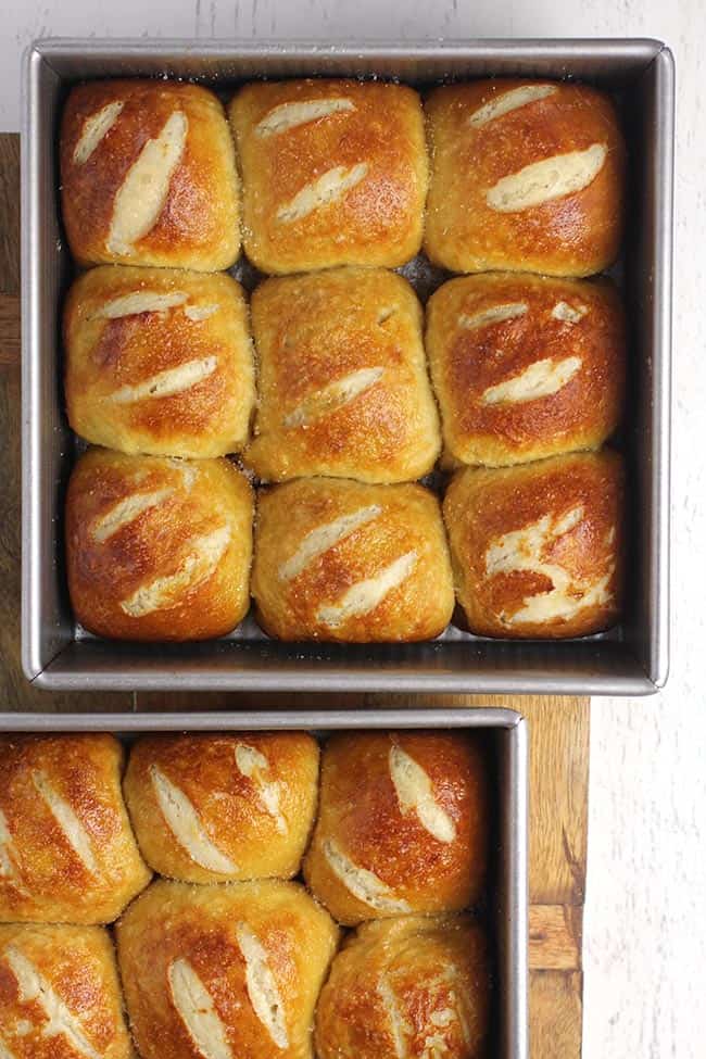 Two pans of just baked pretzel rolls.
