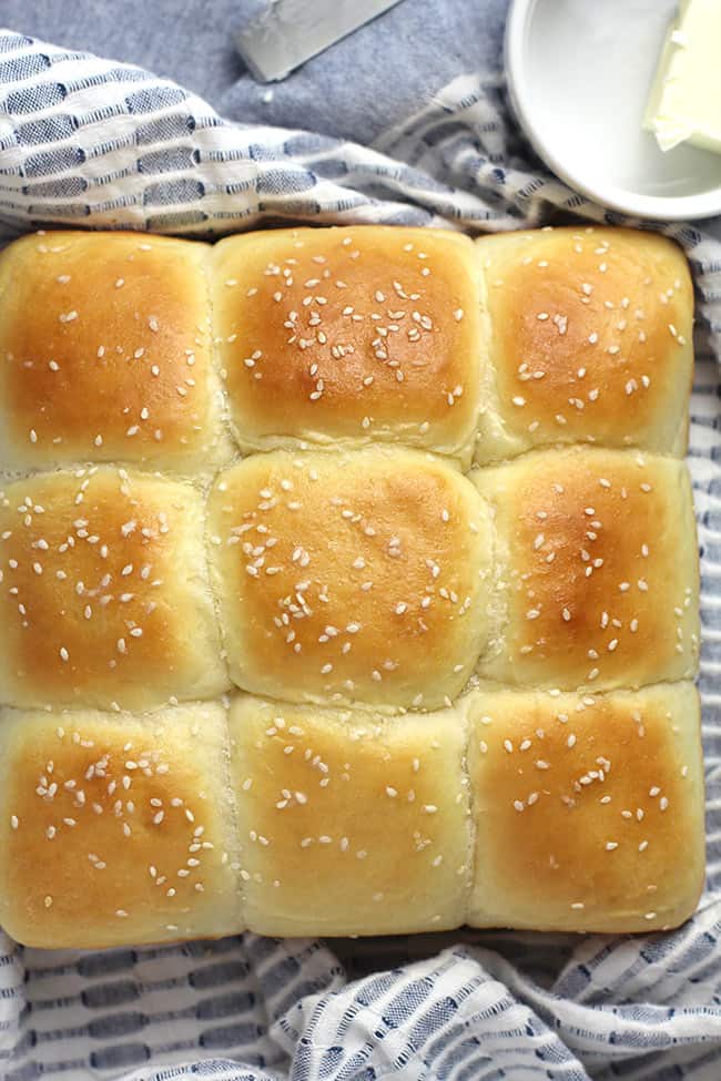Overhead shot of a square loaf of soft brioche diner rolls, on a blue and white napkin.