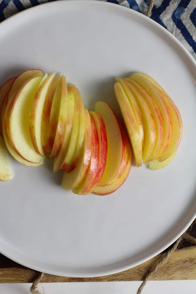 A white plate of thinly sliced apples.