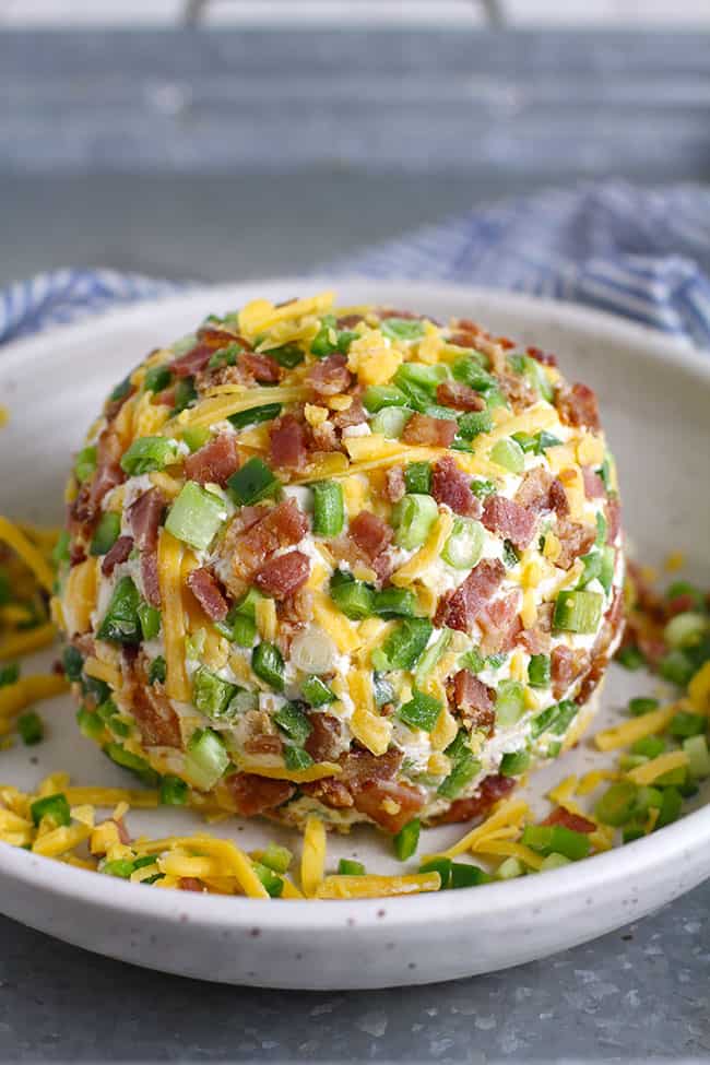 Side view of a cheese ball with all the reserved ingredients on the outside.