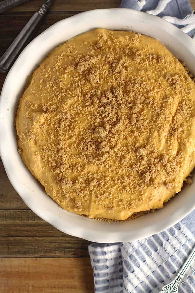 A whole pumpkin ice cream pie with graham cracker crumbs on top.