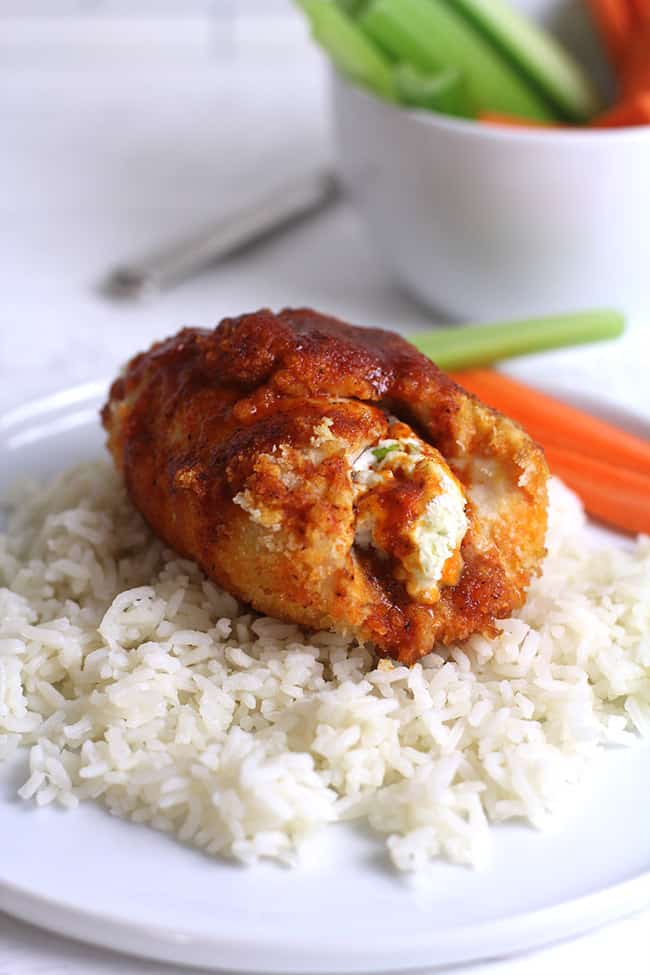 Side shot of a plate of rice with one stuffed buffalo chicken breast.