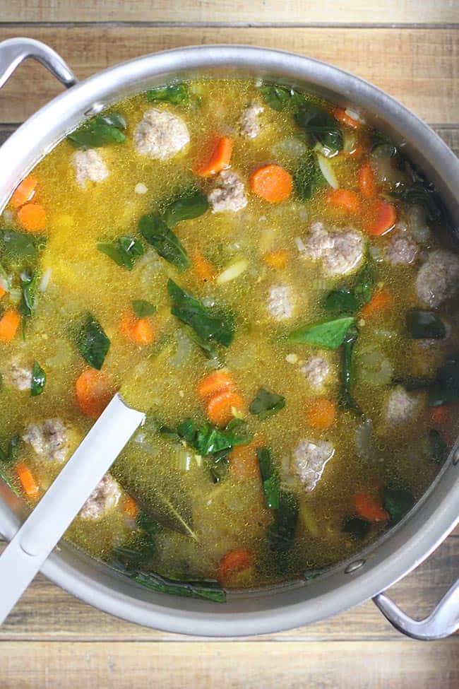 A large stockpot full of Easy Italian Wedding Soup, with a soup ladle inside.