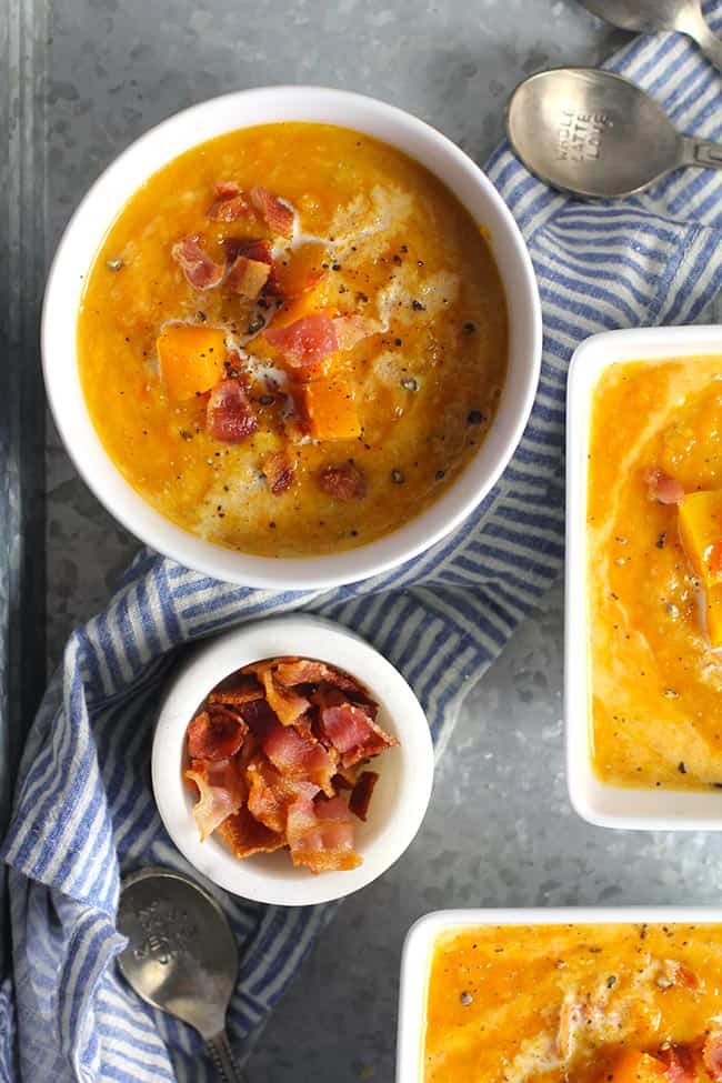 A tray of bowls of butternut squash soup with bacon, with a small bowl of bacon.