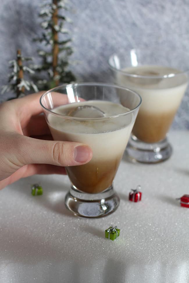 A hand holding a White Russian drink.