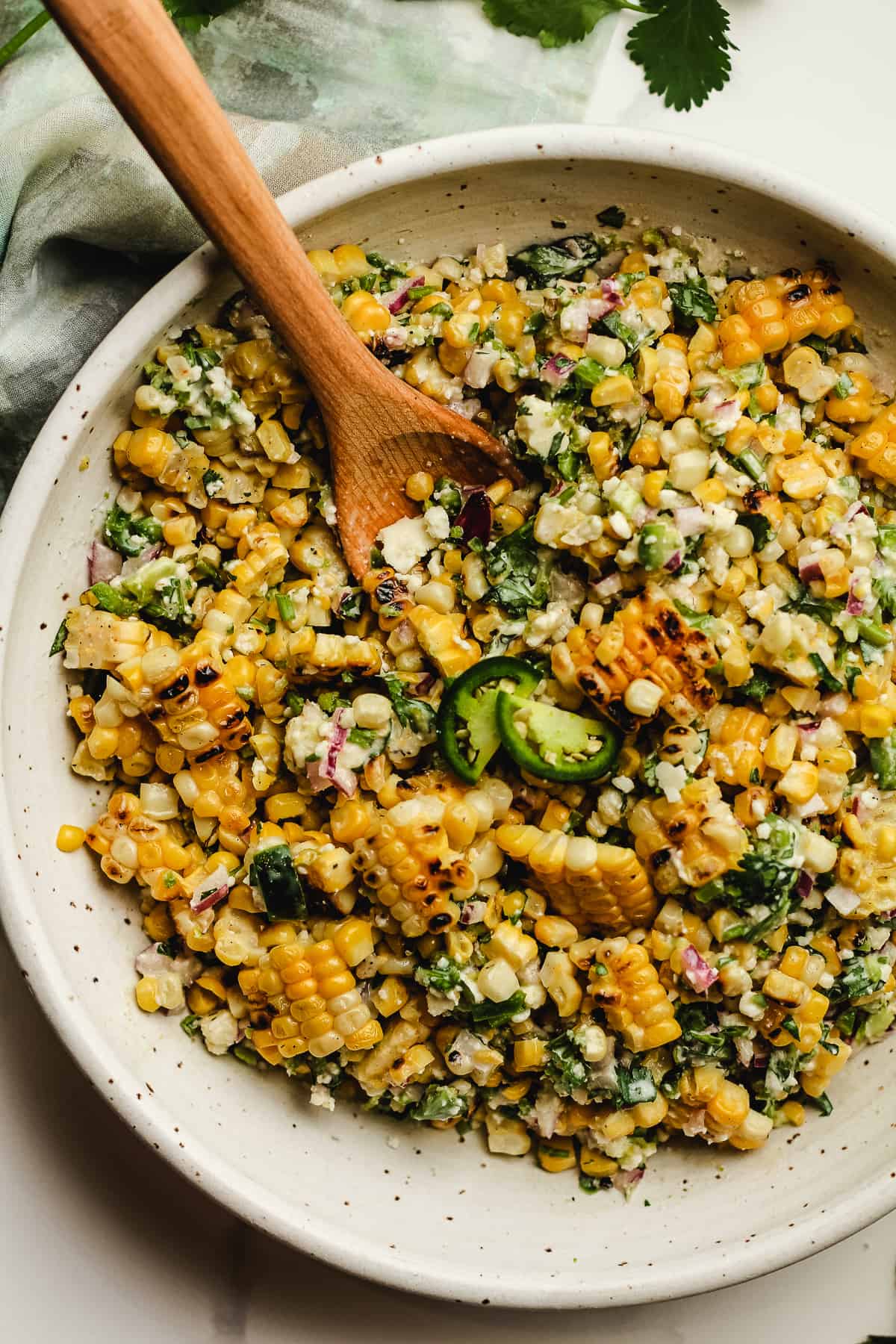 Overhead shot of a bowl of Mexican Street Corn salad, with a wooden spoon.