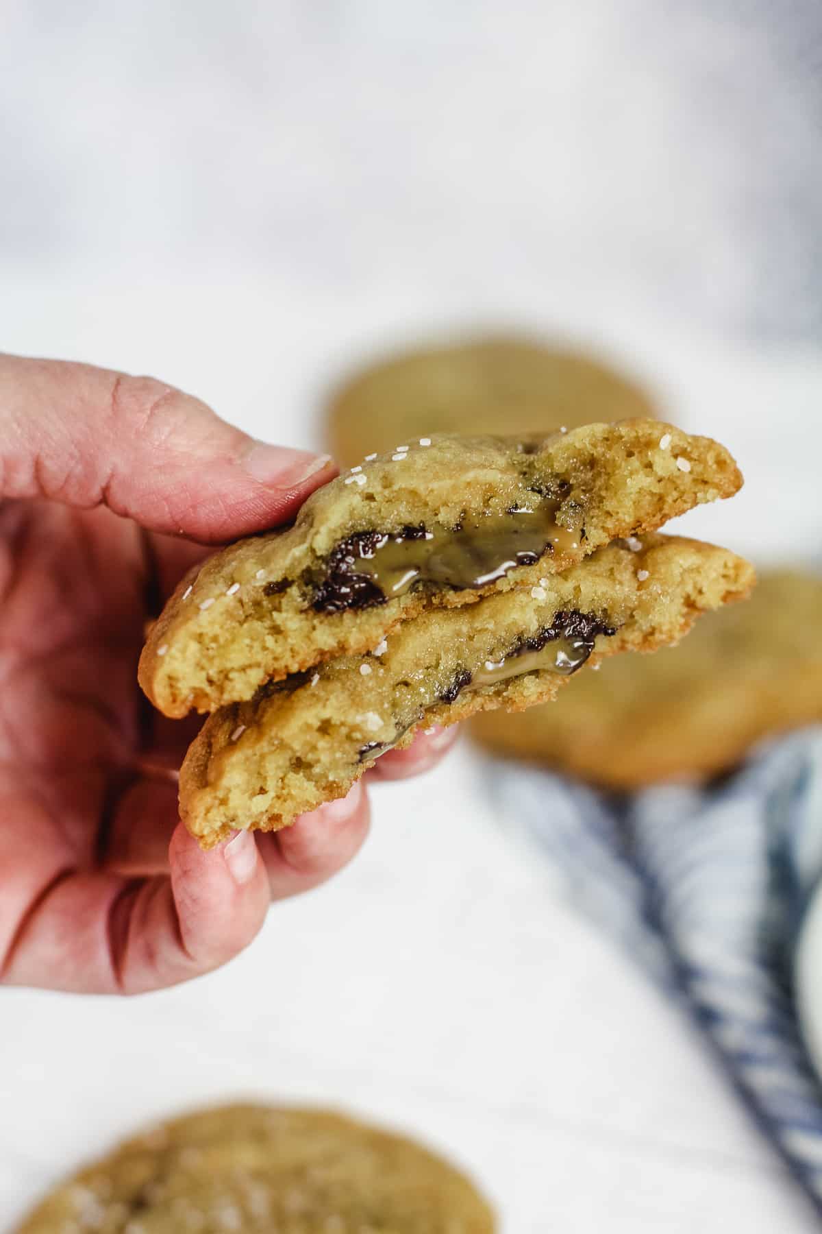 My hand holding two halves of caramel stuffed cookies.