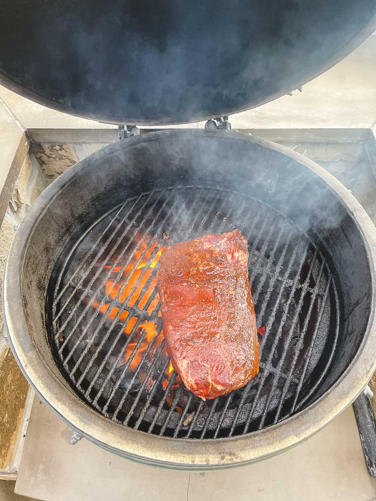 A big green egg grill with a marinated flank steak.