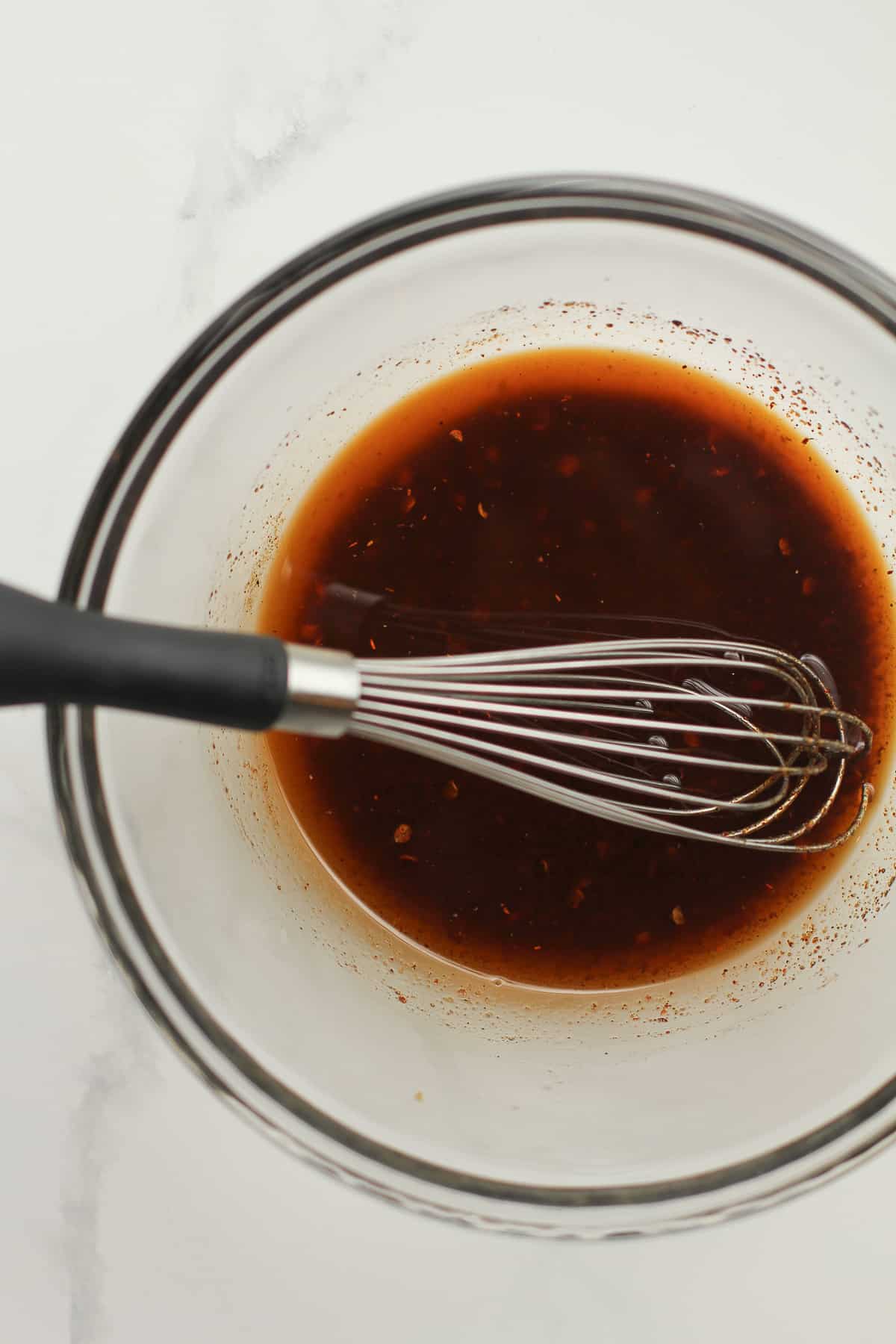 A bowl of marinade with a whisk.