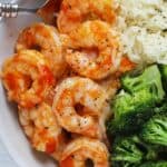 Close up shot of a white bowl of honey sriracha shrimp with rice and broccoli.