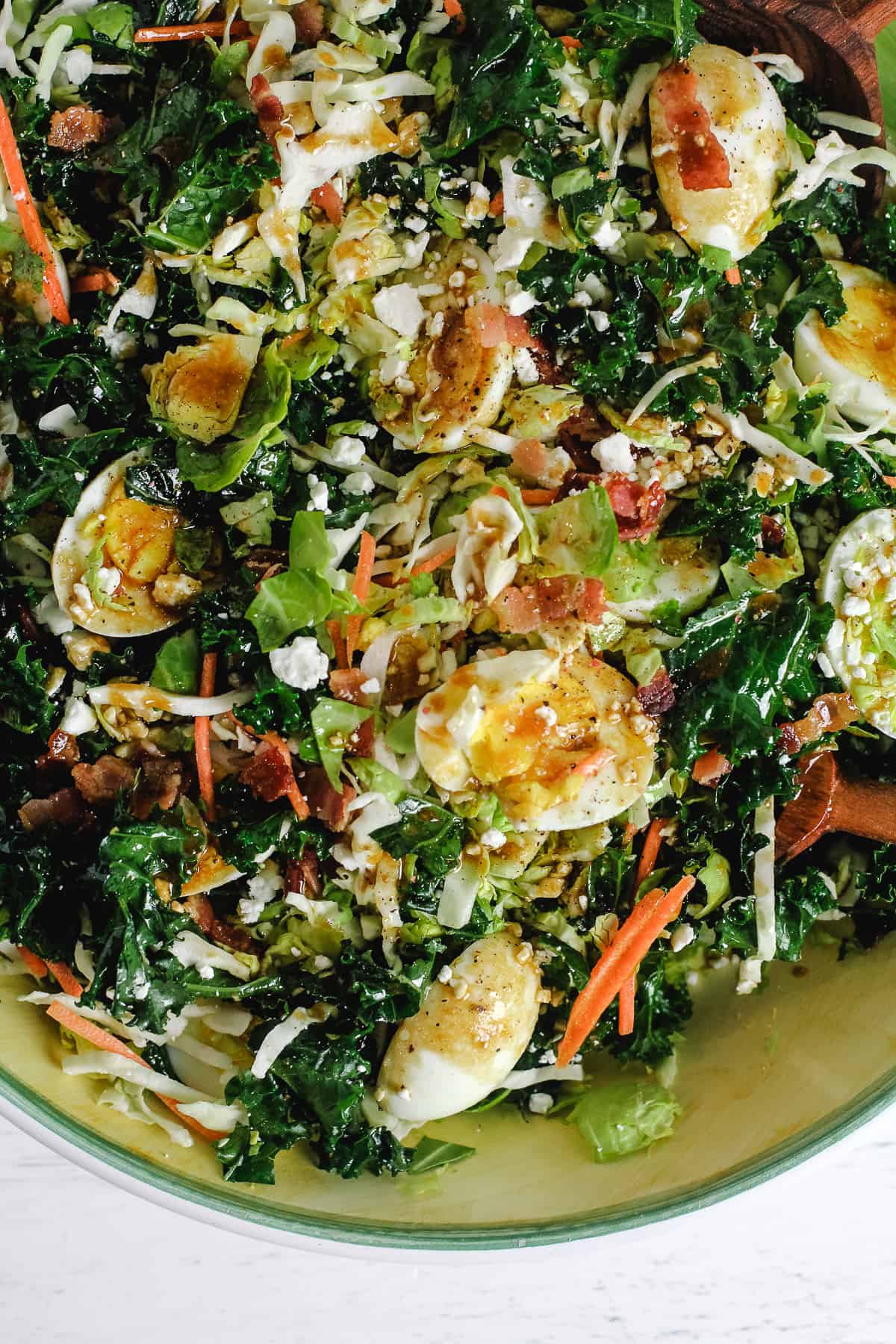 Closeup on cruciferous salad with bacon, eggs, and goat cheese.