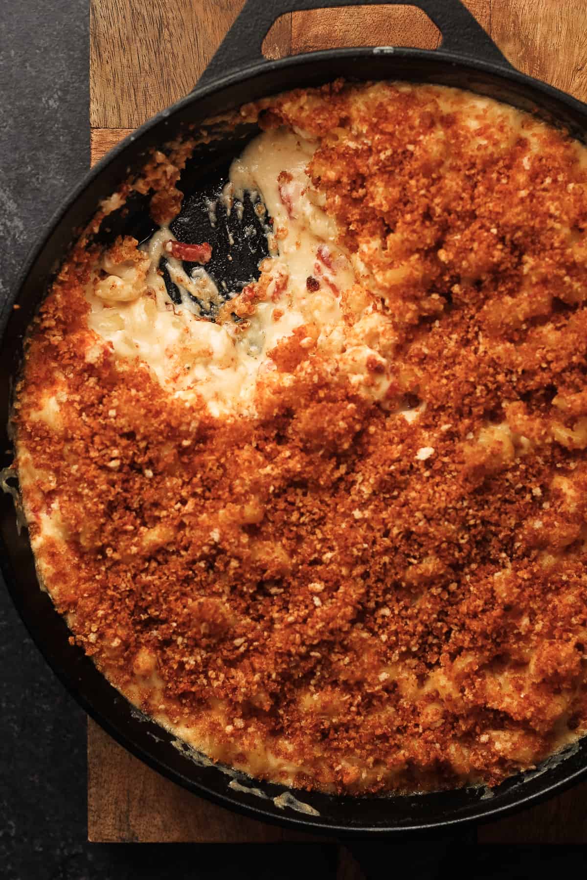 Closeup of cast iron skillet of Mac and cheese, with a large spoonful gone.