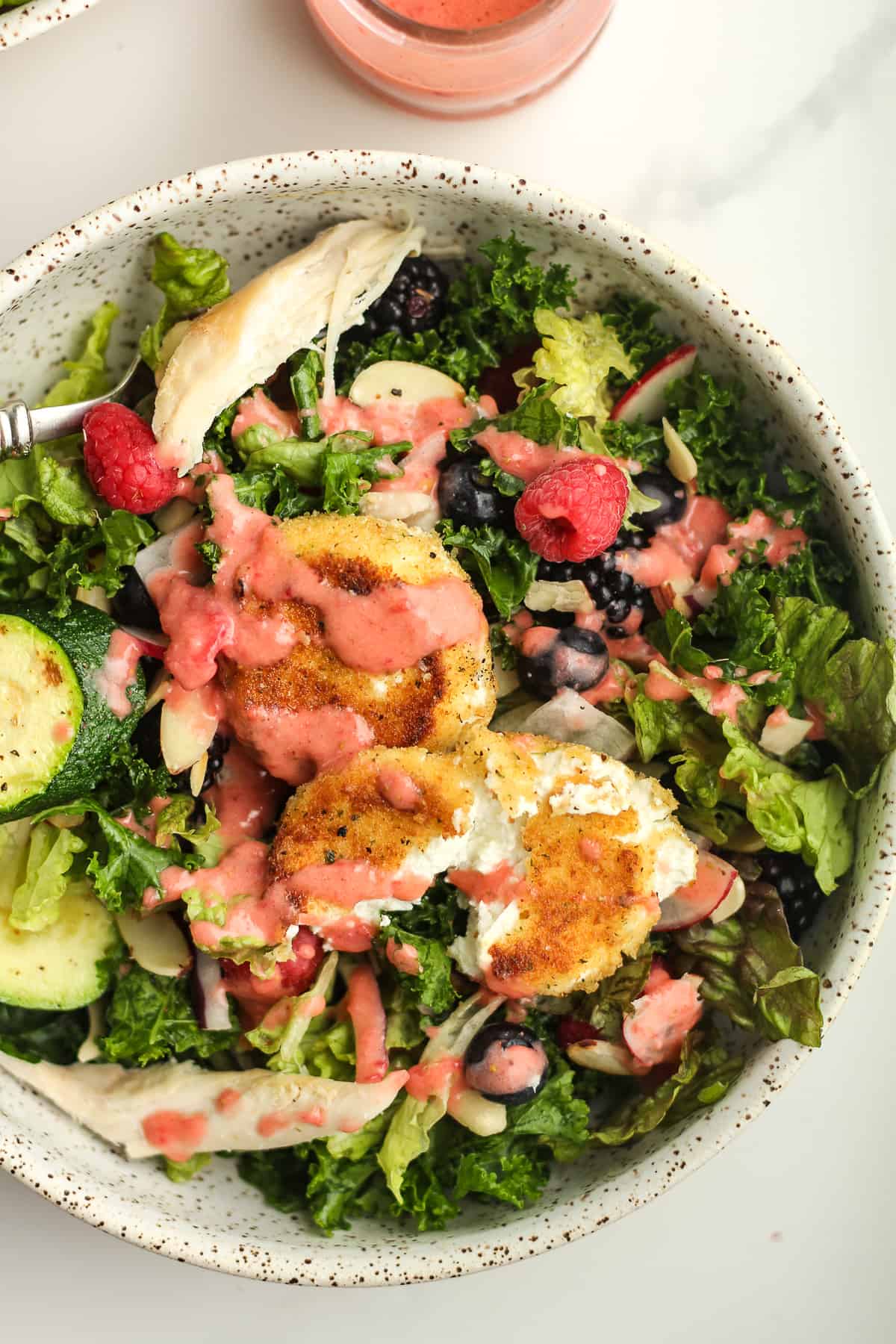 Closeup of a serving bowl of fried goat cheese salad with strawberry dressing.