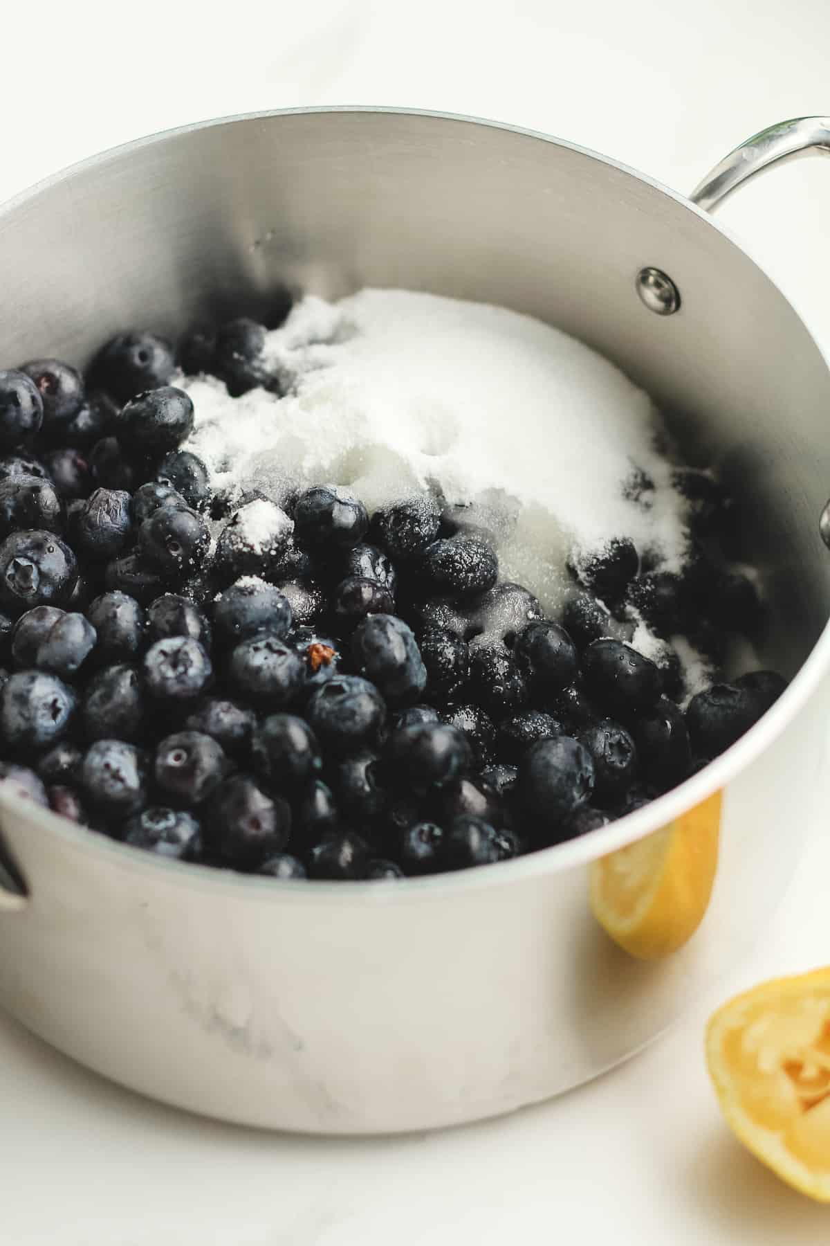 Side shot of a pan of blueberries with sugar and lemon jiuice.