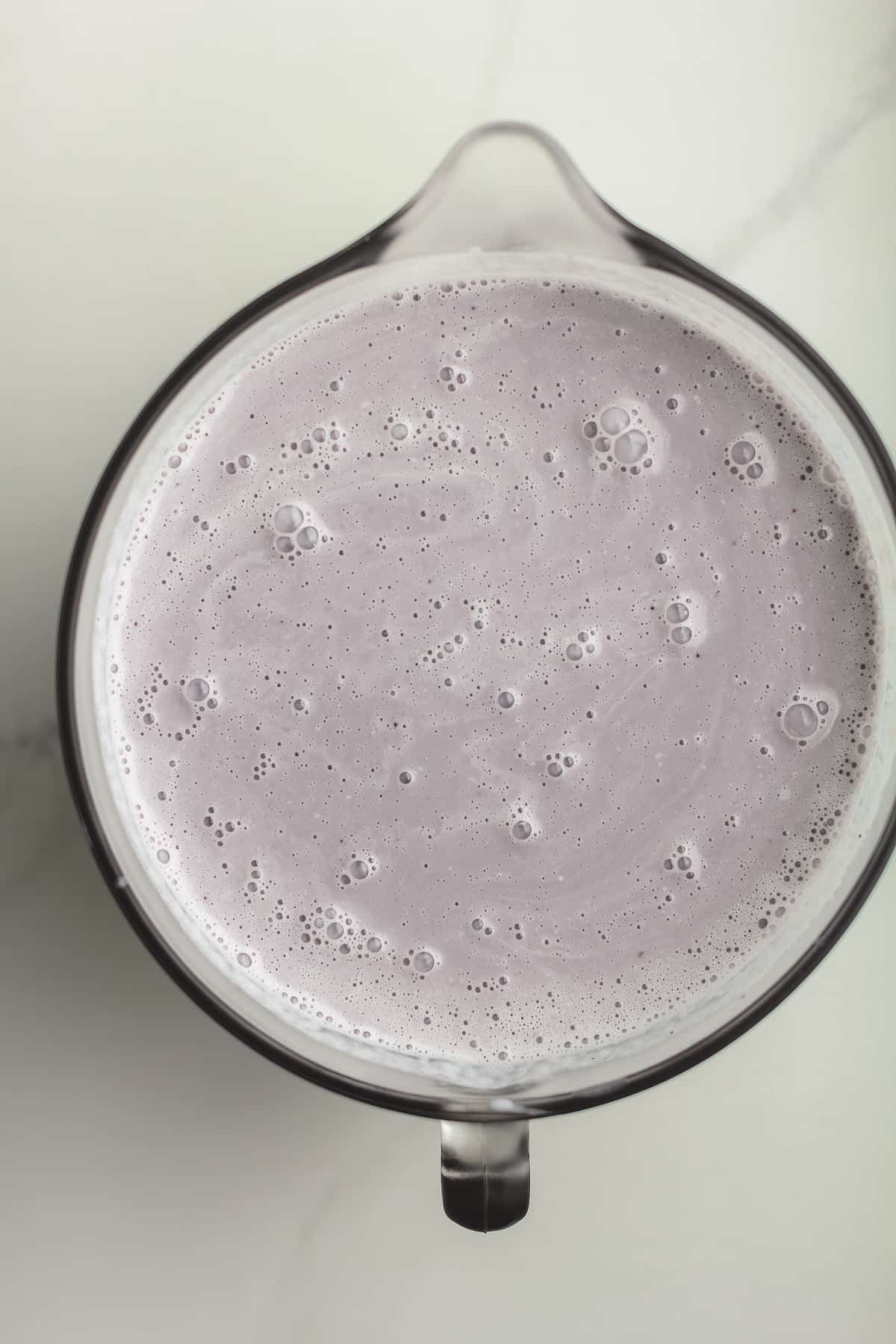 A large measuring cup of the blueberry ice cream mixture.