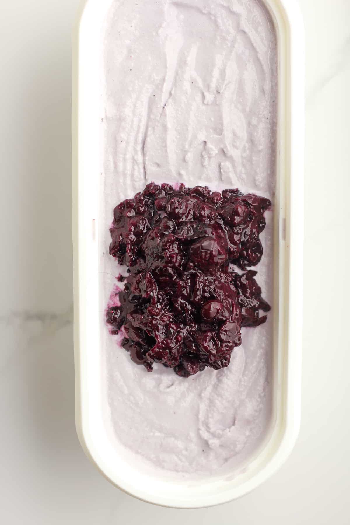 The cooked blueberries on the blueberry ice cream in container.