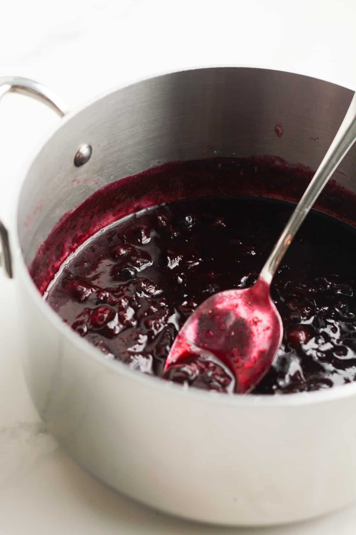 A pan of the cooked blueberries with a spoon.