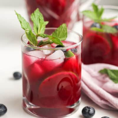 Glasses of blueberry mojitos with fresh mint and blueberries.