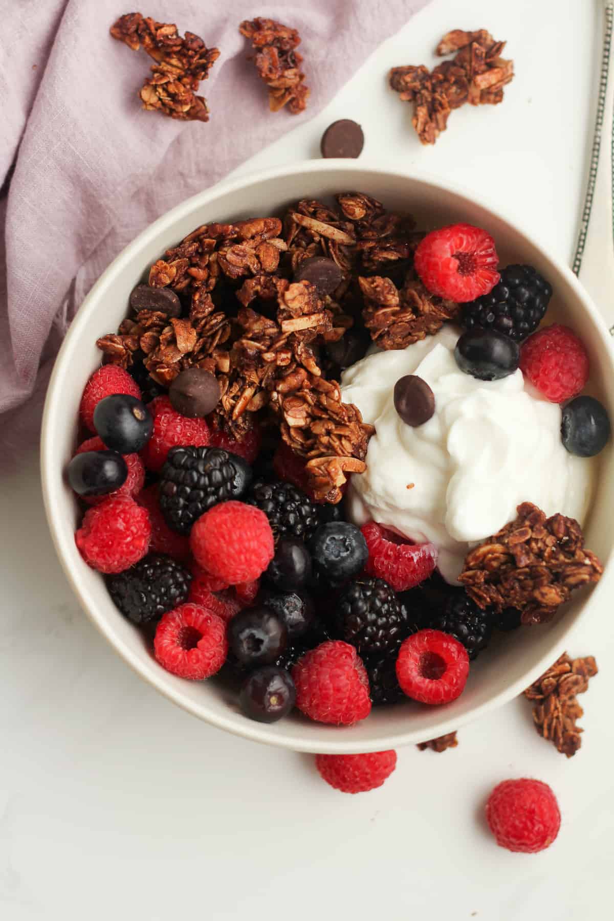 A bowl of yogurt, berries, and chocolate granola.