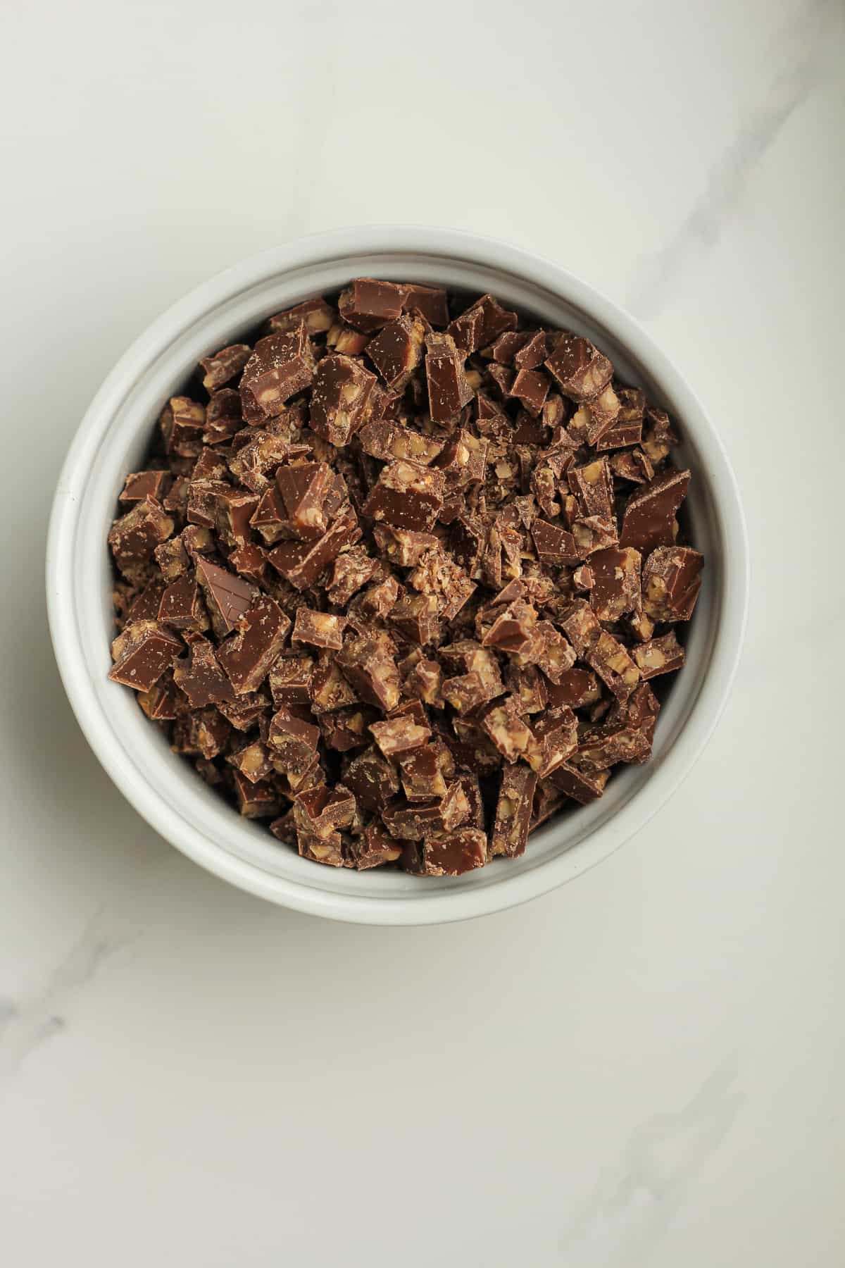 A white bowl of chopped toffee candy.