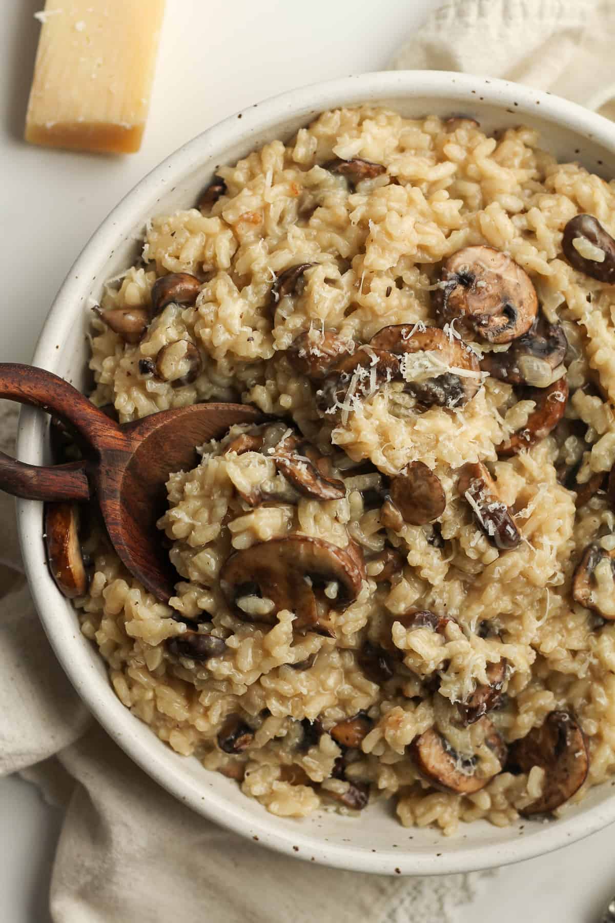 Overhead shot of a bowl of creamy mushroom risotto, with a wooden spoon.