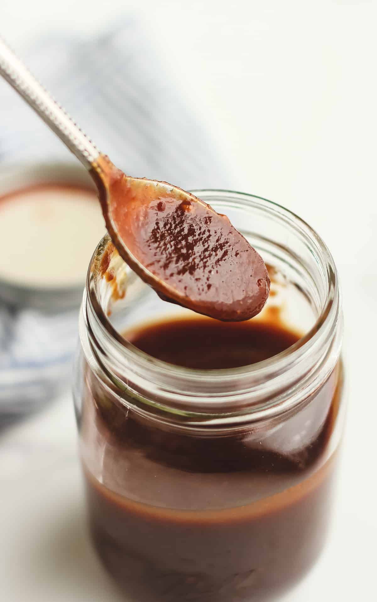 A spoonful dripping some barbecue sauce.
