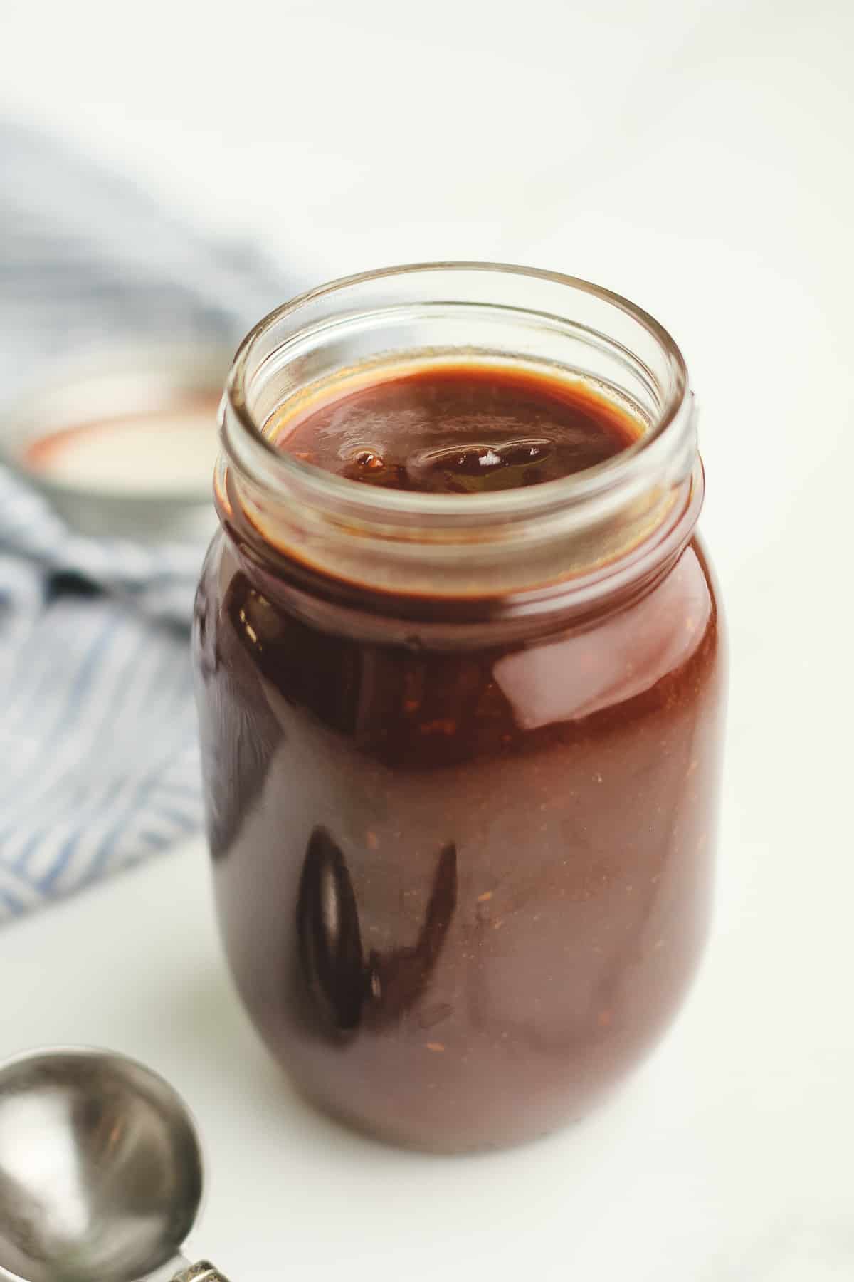 Side shot of a jar of homemade barbecue sauce.