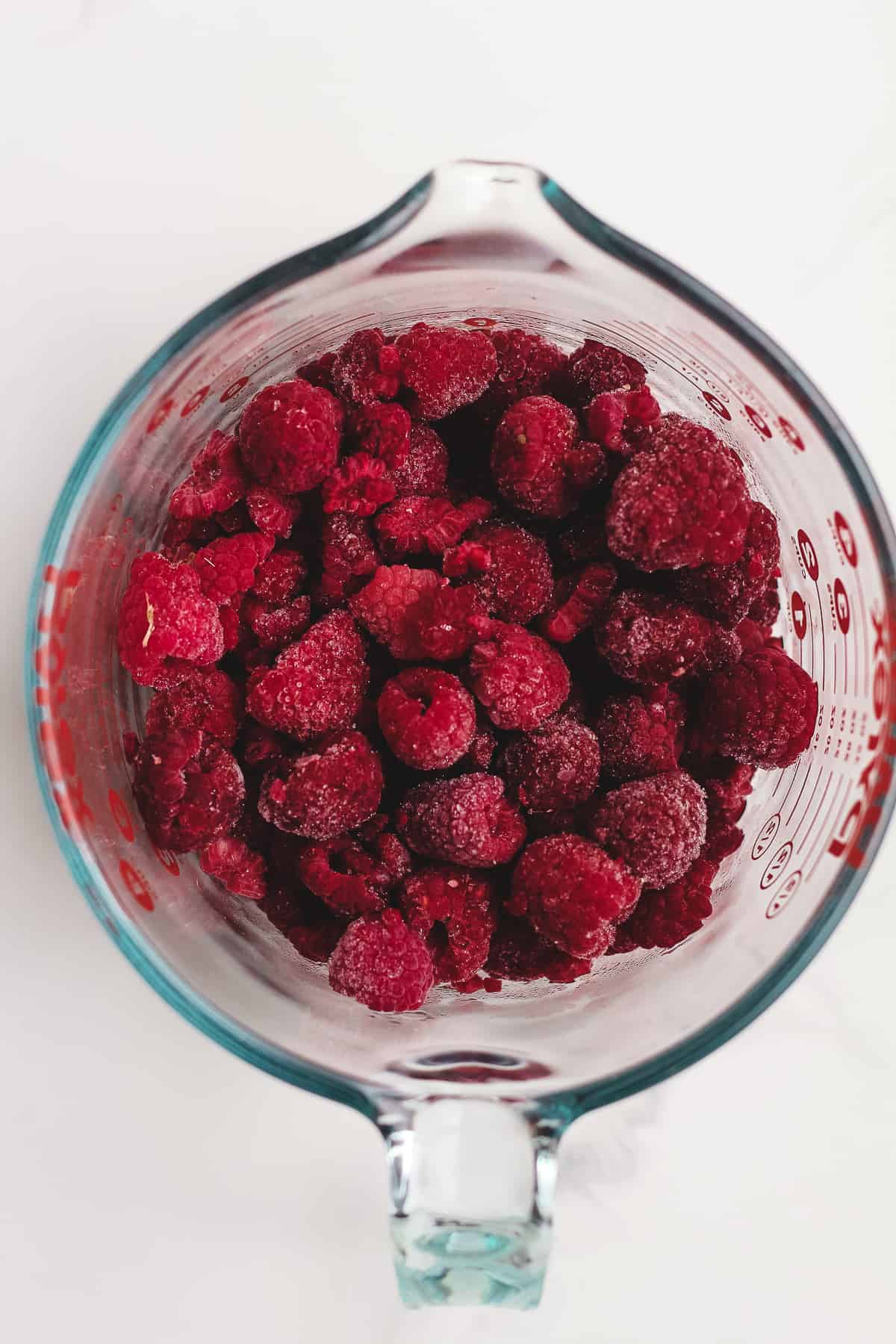 A measuring glass of frozen raspberries.