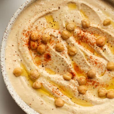 A bowl of hummus with chickpeas on top.