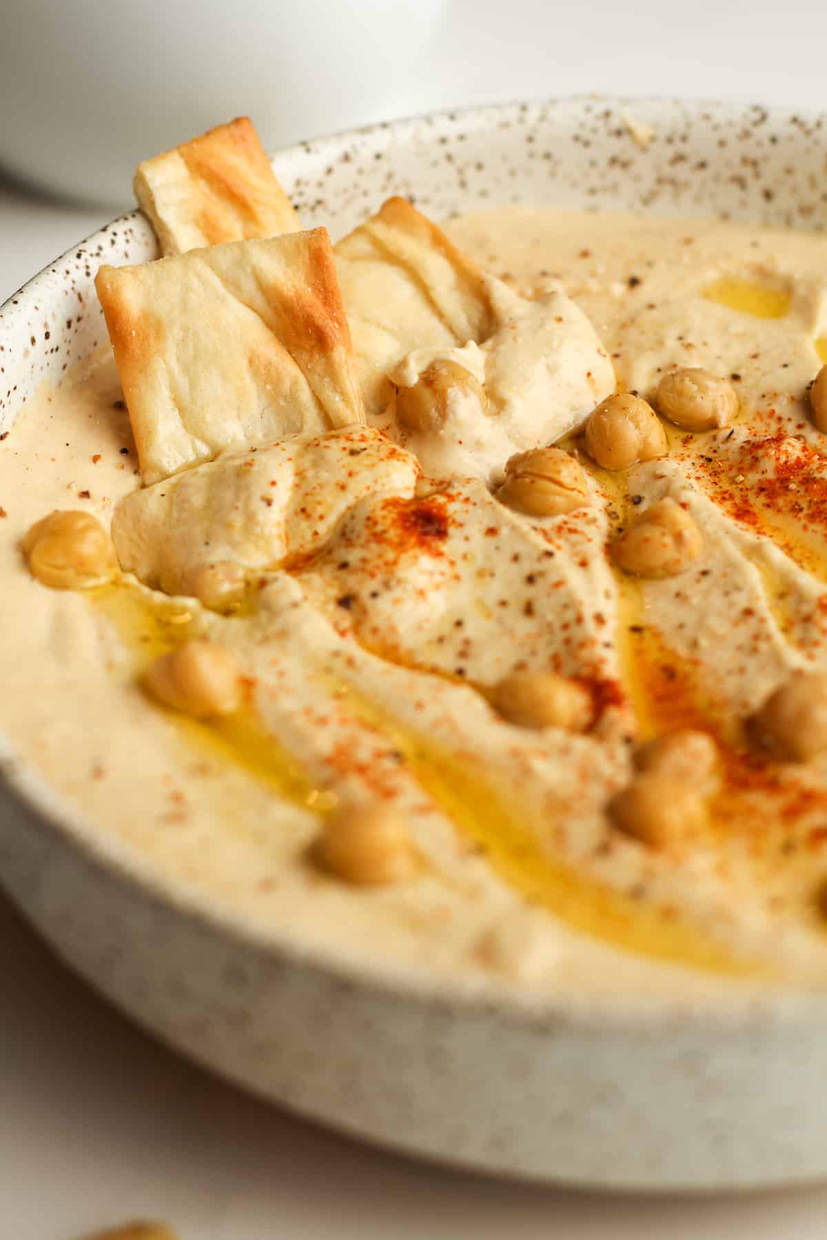 Side shot of a bowl of creamy hummus, with pita chips.