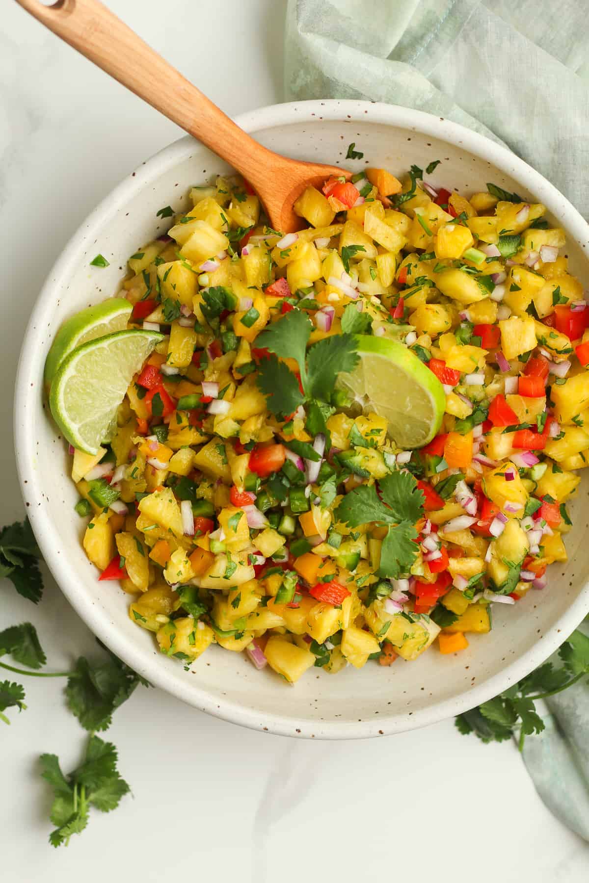A bowl of pineapple salsa, with lime wedges.