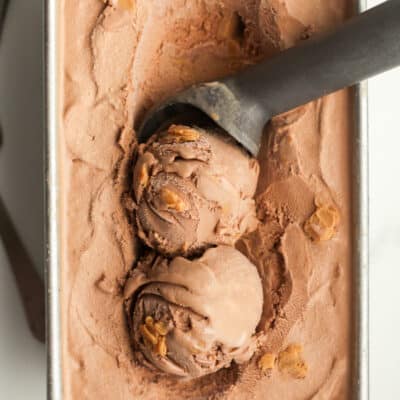 Closeup of a pan of ice cream, with two scoops and the ice cream scooper.