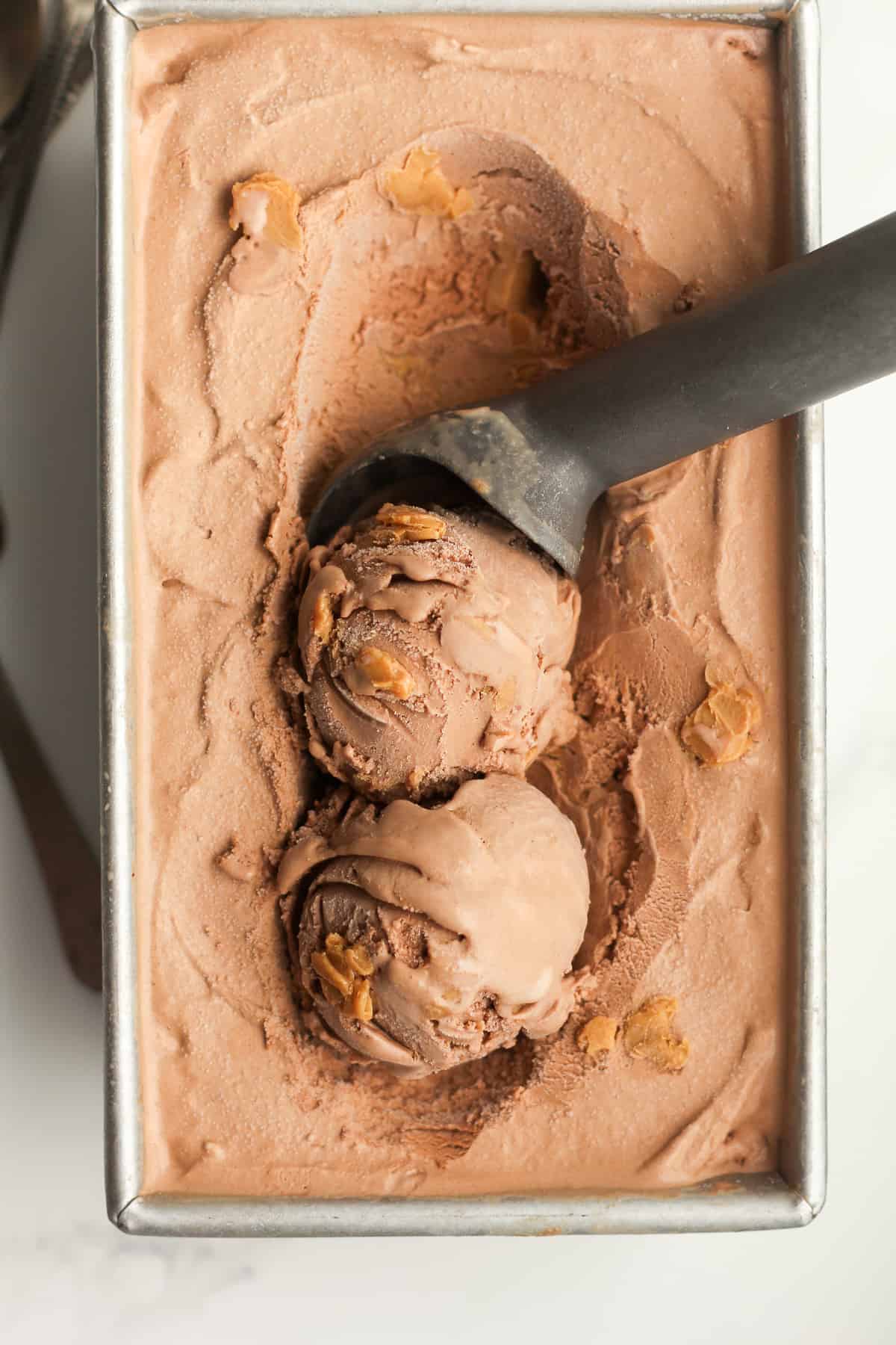 Closeup of a pan of ice cream, with two scoops and the ice cream scooper.