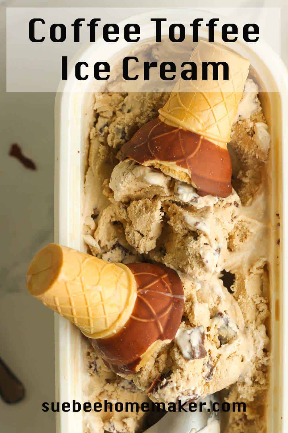 A container of coffee toffee ice cream, with two cones in the middle.