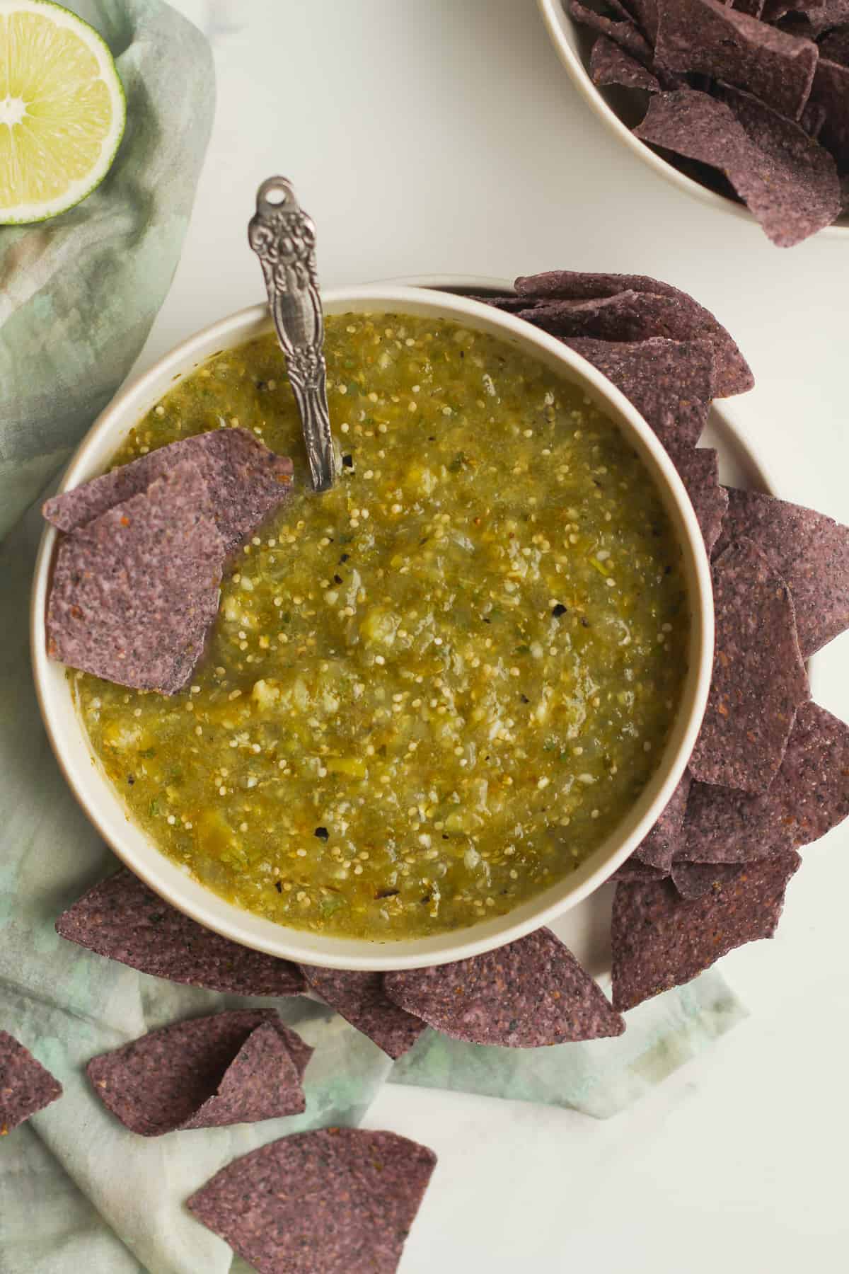 Overhead shot of a bowl of salsa verde with blue chips.