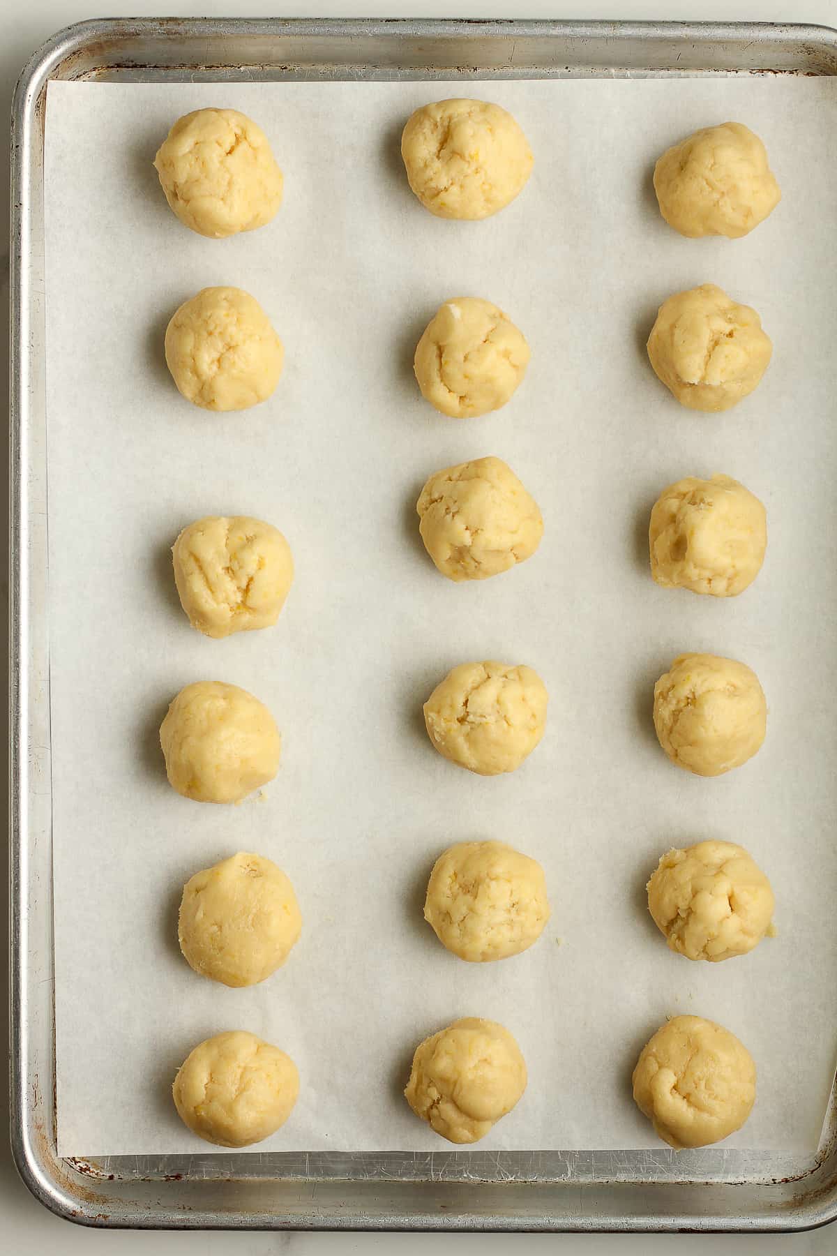 18 lemon sugar cookie balls on a tray.