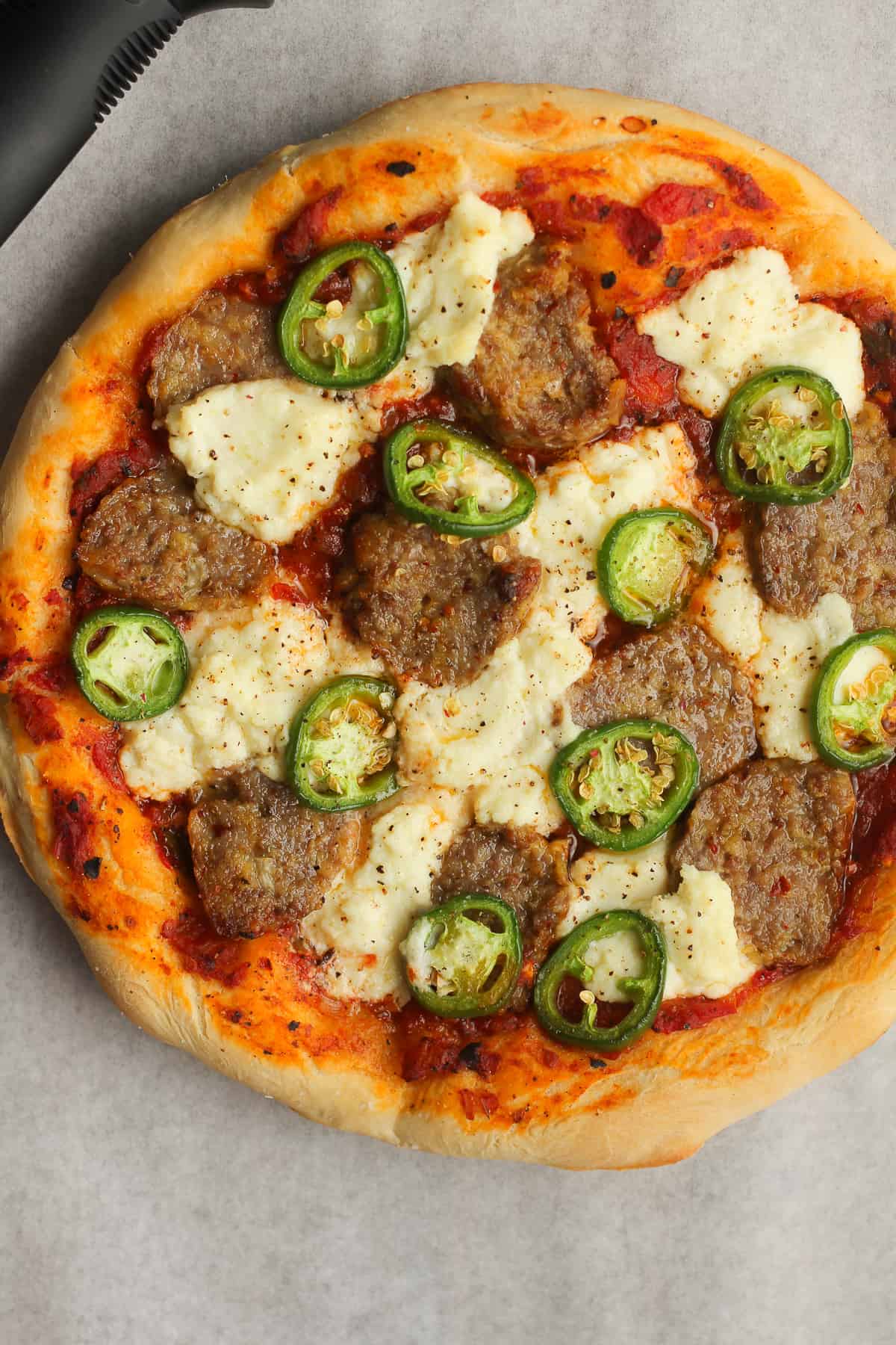 A meatball pizza with ricotta, before slicing.