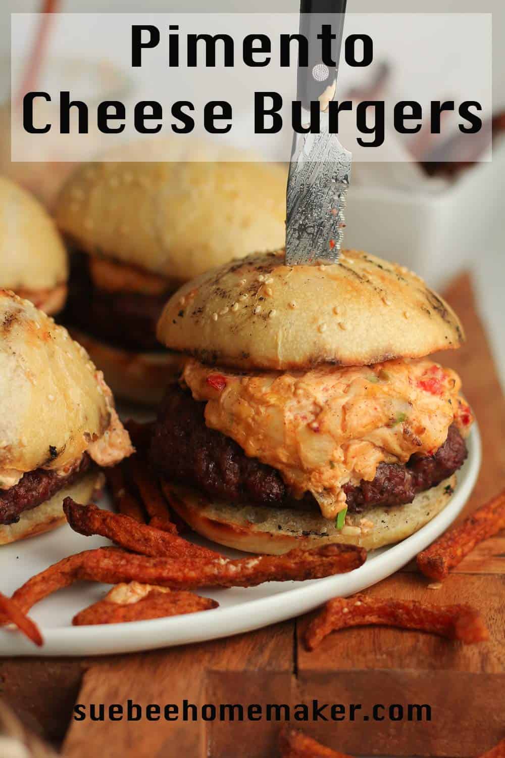 A plate of pimento cheese burgers, with a knife in one.