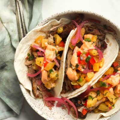 A bowl of three pork tacos with pineapple salsa.