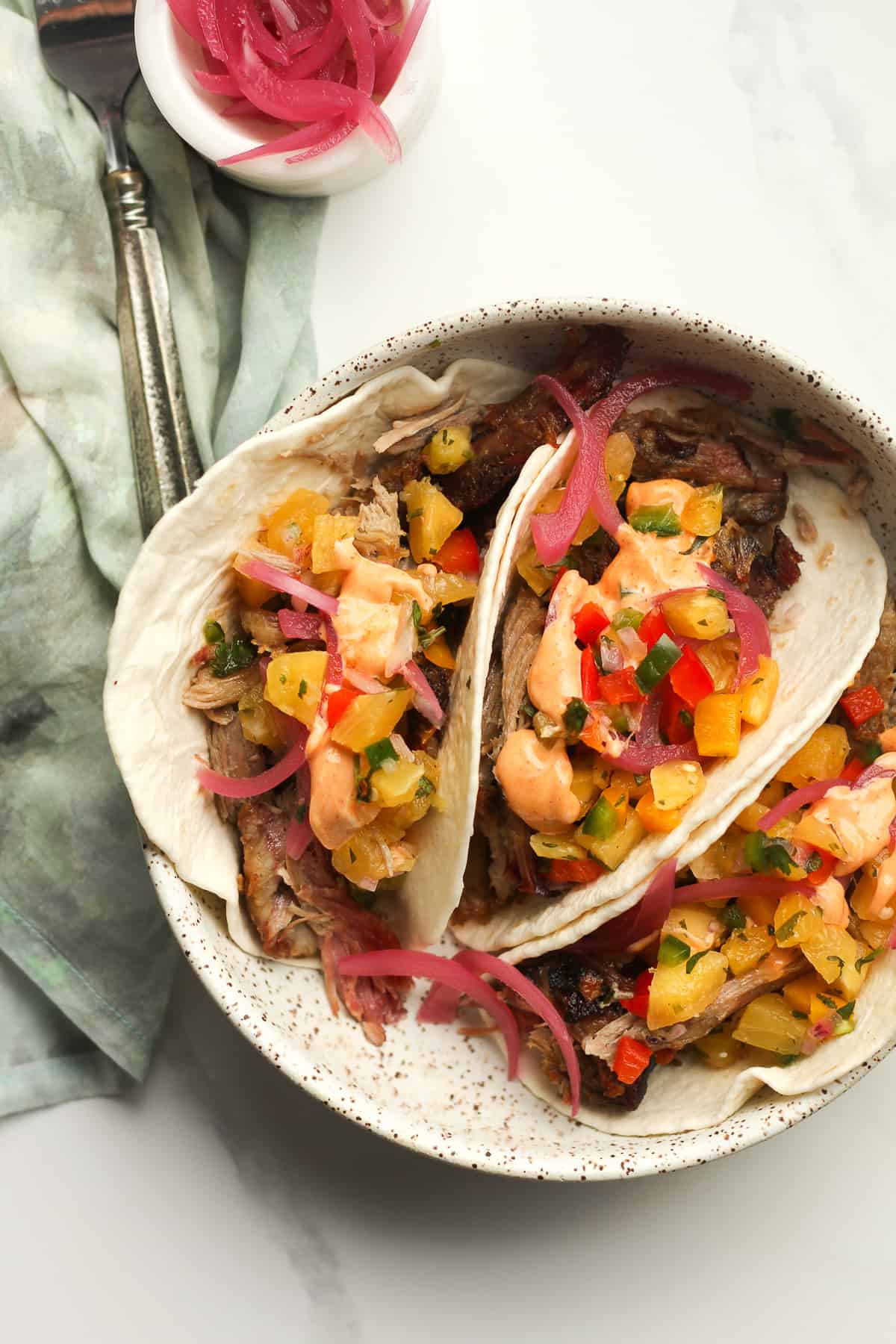 A bowl of three pork tacos with pineapple salsa.